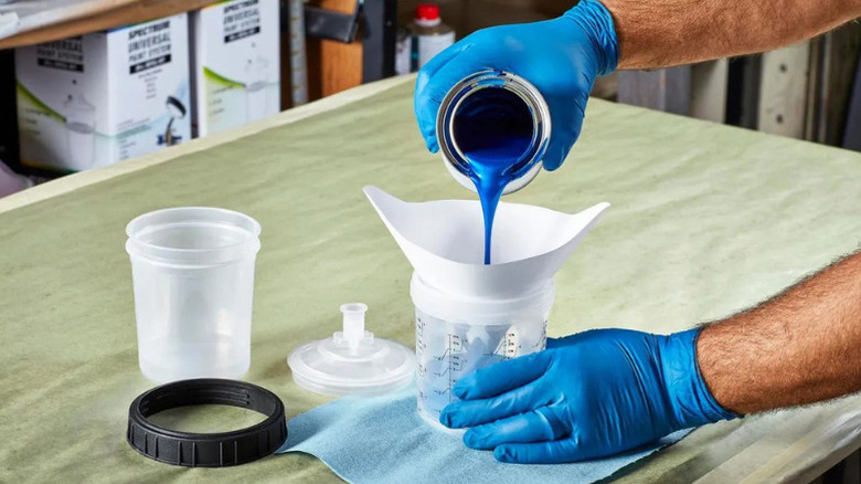 A person filling a paint pot liner bag with blue paint
