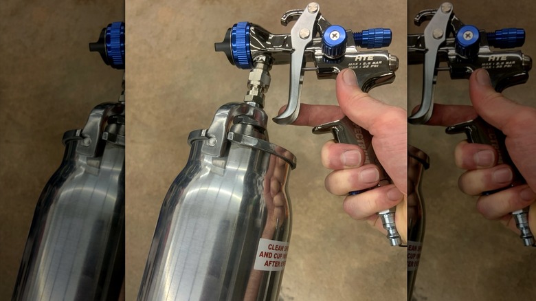 Hand holding Spectrum's 32 ounce Professional HTE Compliant Siphon Air Spray Gun