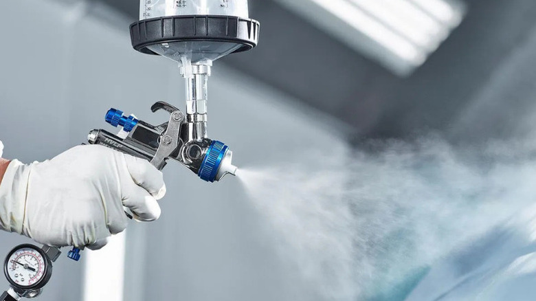 A person using Spectrum's Premium HVLP Gravity-Feed Air Spray Gun with Side Fan Control, 1.7mm Nozzle