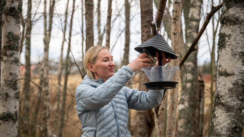 A woman refilling a bird feeder