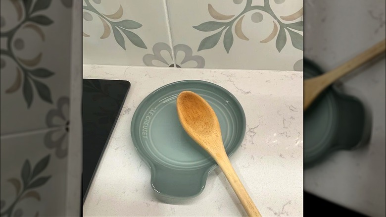 Vintage style blue gray spoon rest with wooden cooking spoon on kitchen counter