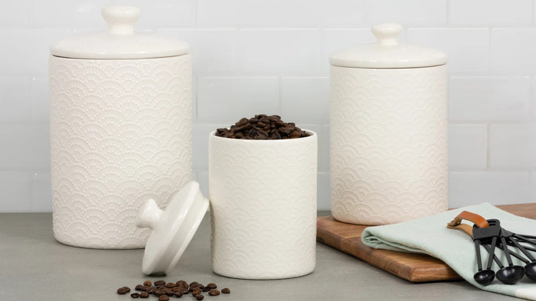 Decorative white kitchen cannisters on countertop filled with coffee beans
