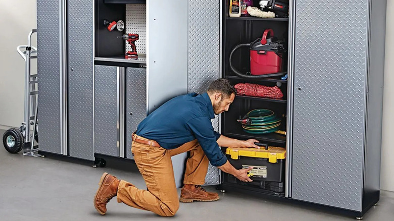 A man takes a toolbox out of a cabinet.