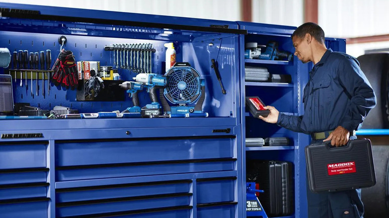 A man stands in front of an end locker full of tools.