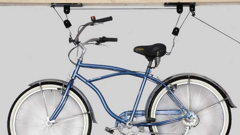 A bicycle hangs from the ceiling by a mounted pulley system.