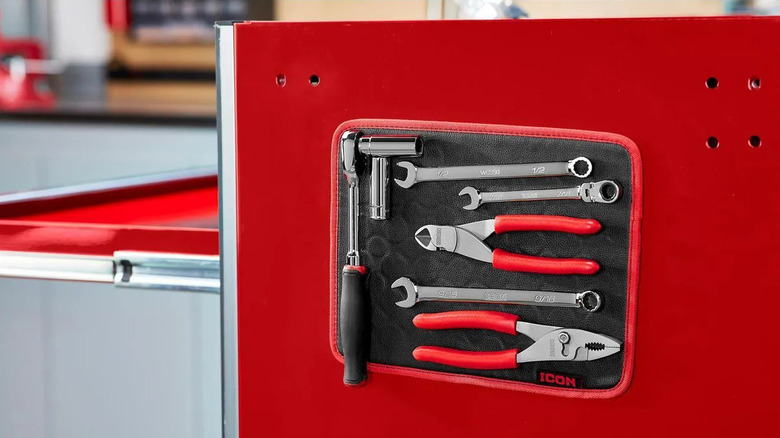 A magnetic mat holds tools on the side of a metal toolbox.