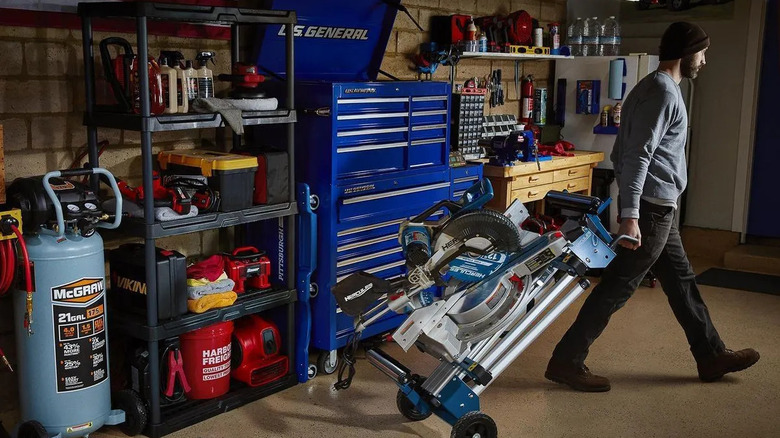 A man is walking away from a 5-tier shelf in a garage.