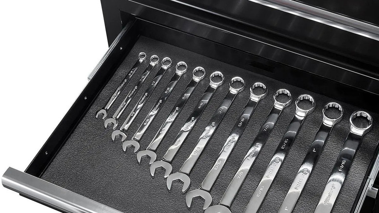Wrenches sit in the drawer of a mobile cart.