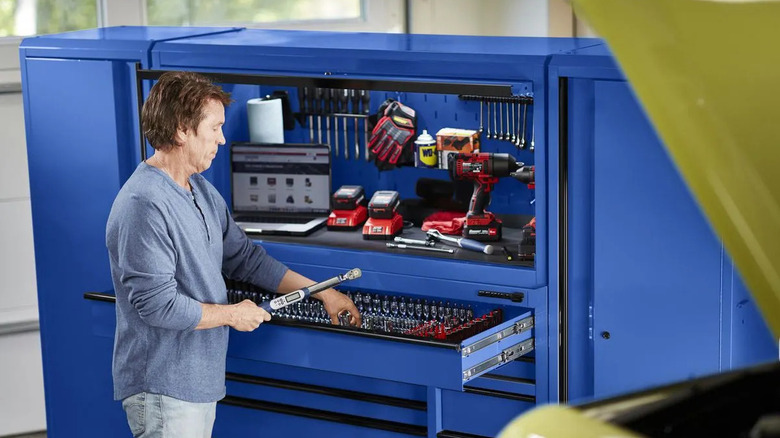 A man puts tools into a workstation.
