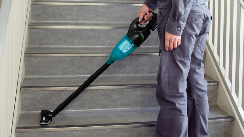 A person using Makita's 18V LXT Lithium-Ion Handheld Compact Cordless Vacuum