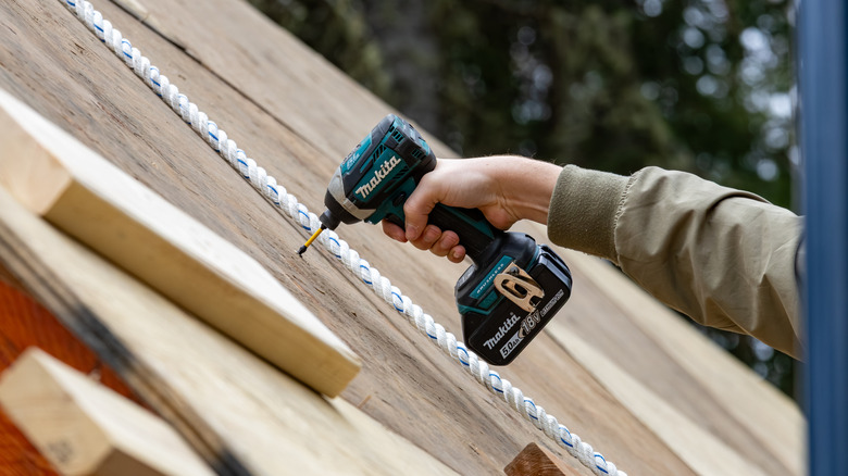A person using a Makita drill to drive fasteners into wood
