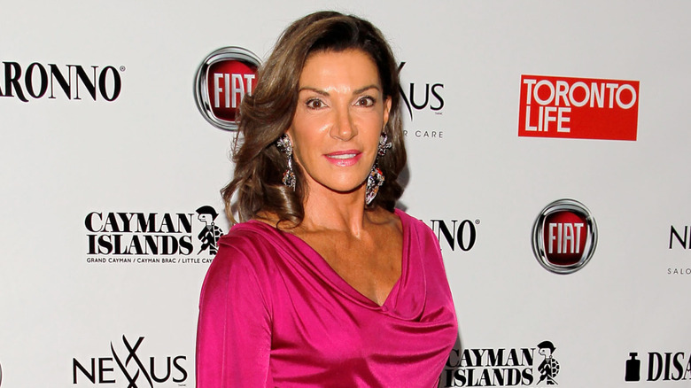 Hilary Farr posing in front of red carpet backdrop