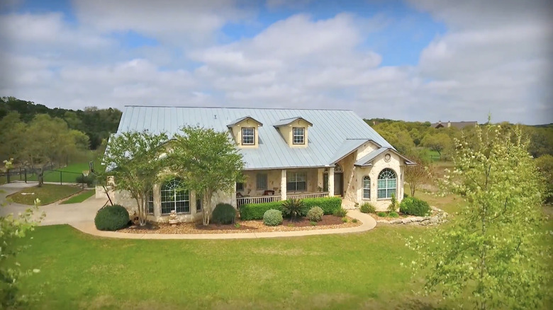 A classic Hill Country home with stone exterior, a covered porch, and a metal roof, surrounded by nature.