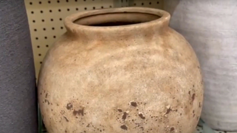A light brown accent vase sitting on a shelf