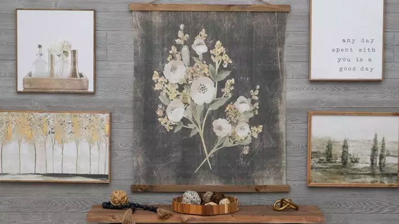 A wall of canvases with a tapestry in the middle