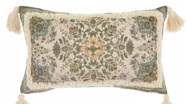 A green and cream colored pillow with white tussles