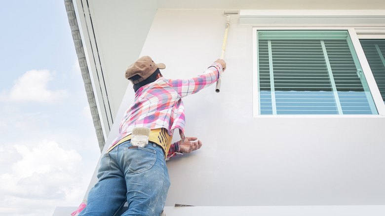 person painting a home's exterior