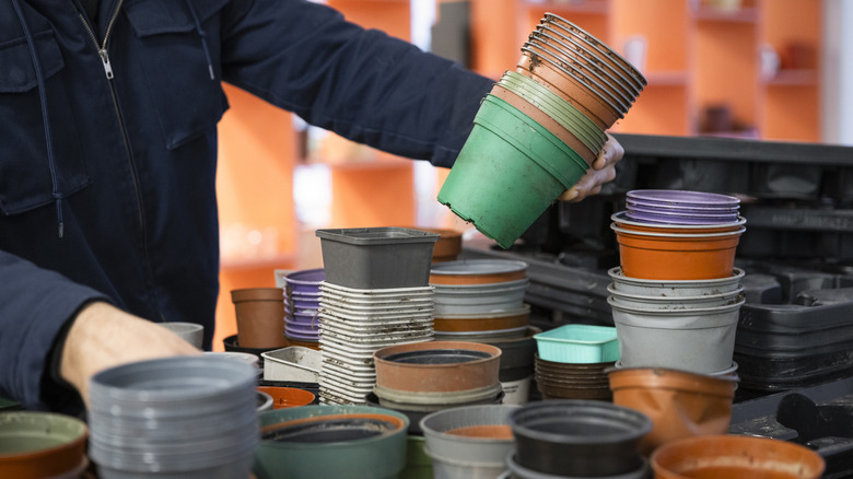A person piles plastic nursery pots on top of each other.