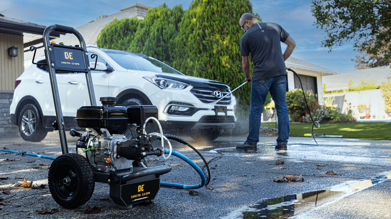 A man cleaning a car with a BE Power 3400 PSI 2.4 GPM Gas Pressure Washer