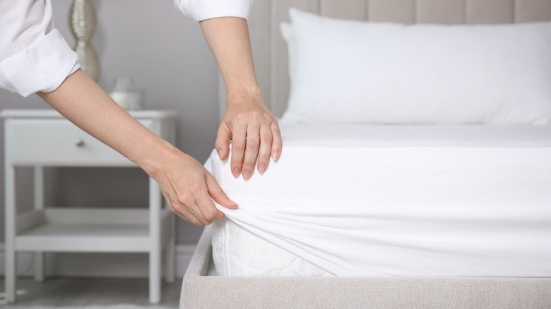 A person putting sheets on a bed