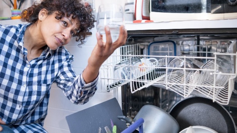 woman inspecting glass from dishwasher