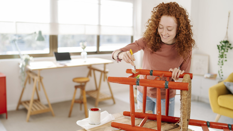 A person painting a wooden chair