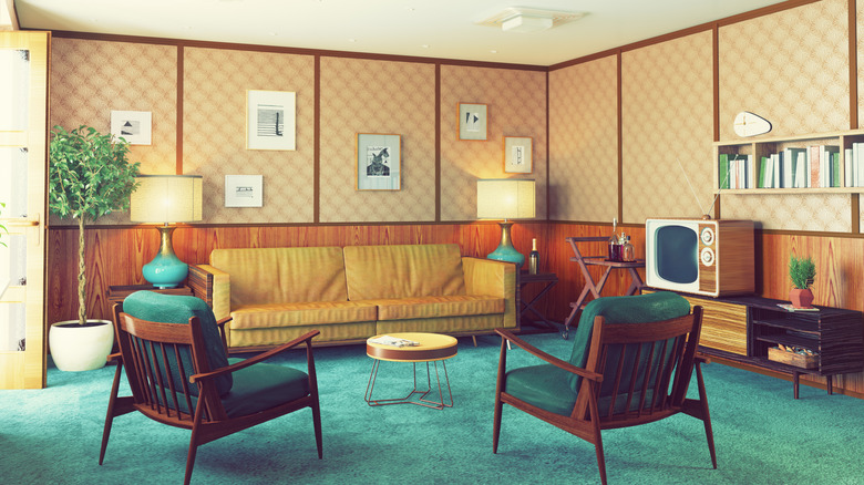 A typical '50s living room, with jewel-tone accents, light wood, wood furniture, and wood paneling.