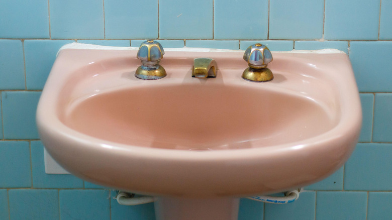 A pastel pink sink on a pastel blue-tile wall exemplifies a 1950s trend