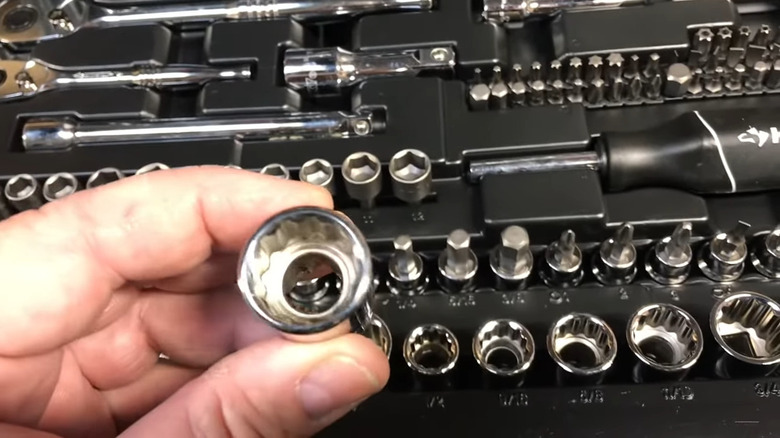 Hand holding a socket above a Husky tool set