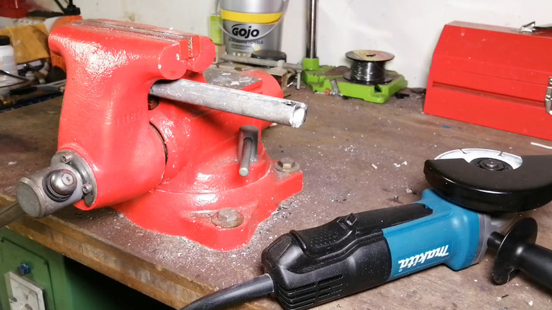 View of a Makita paddle grinder on a dust tool shop next to a vice with a piece of wood