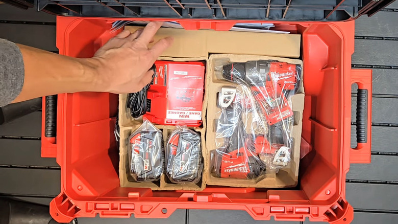 Top down view of man's hand opening a Milwaukee M18 FUEL 18V Lith-Ion Cordless Combo Kit,