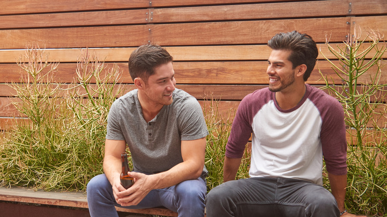 Two friends in front of a privacy fence consisting of horizontal wood beams