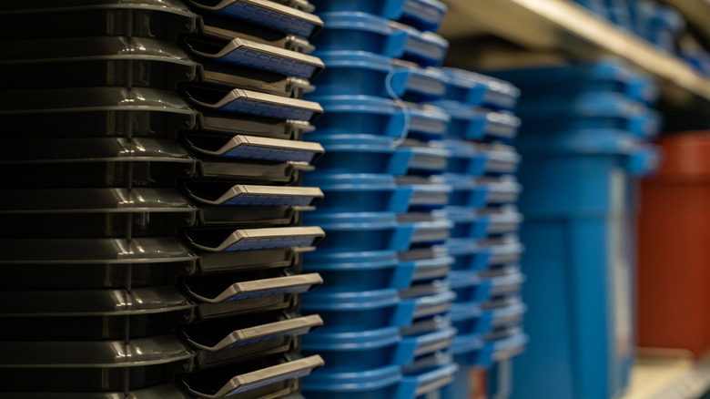 Stacked plastic storage bins with lids in hardware store aisle.