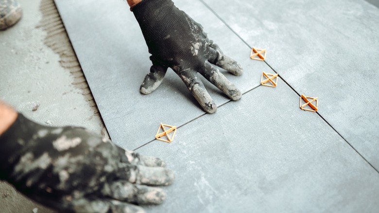 person installing tiles on floor