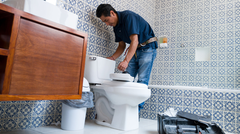A plumber installing a toilet in a bathroom