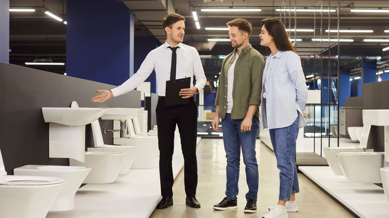 A salesman showing customers a series of toilets