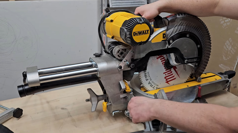 Person demonstrating a DeWalt miter saw on a piece of wood