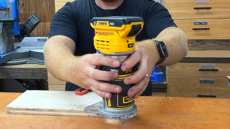 a man demonstrating the use of a DeWalt compact router