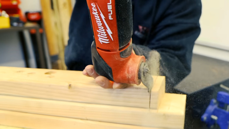 a person using the Milwaukee M18 multitool to cut a piece of wood