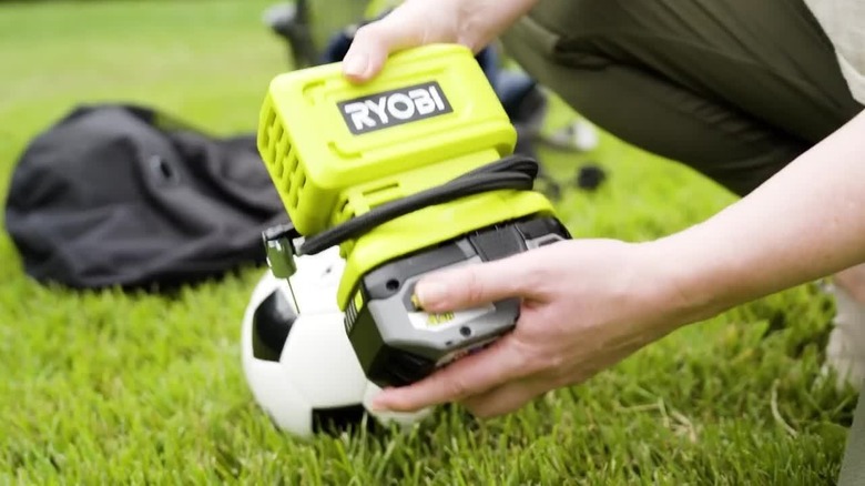 a Ryobi inflator tool with a high performance battery being used to inflate a soccer ball