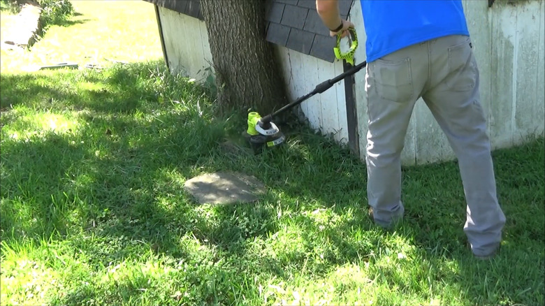 a person using a Ryobi 18V string trimmer to cut tall grass