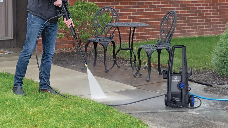 a man using the Westinghouse ePX3030 electric pressure washer on a cement walkway