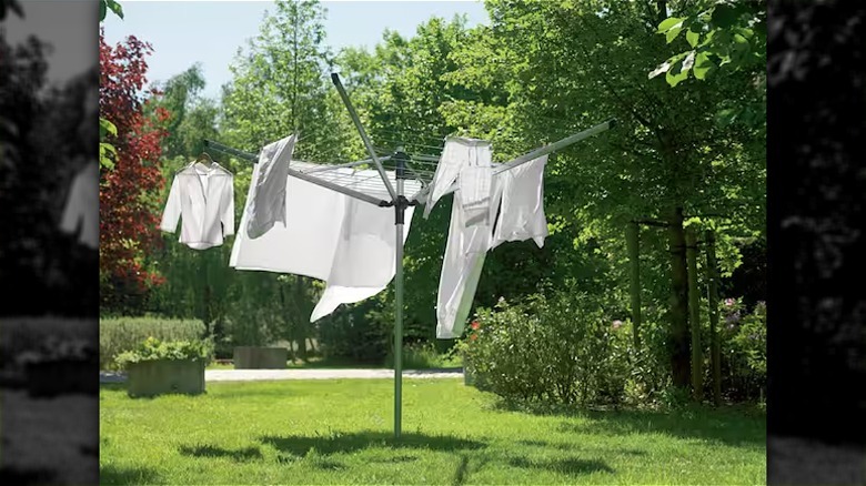 White laundry dries on a rotary clothesline in a yard.