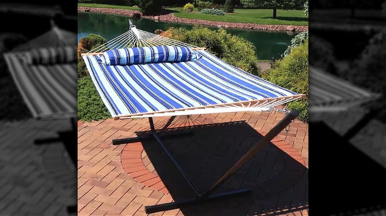 A smiling woman in a red dress lounges on a blue striped hammock.
