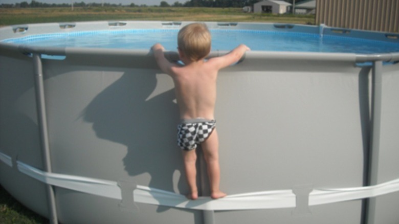 Child standing on a compression strap at a swimming pool