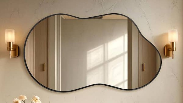 Irregular black aluminum alloy framed wall mirror hanging on a textured white wall