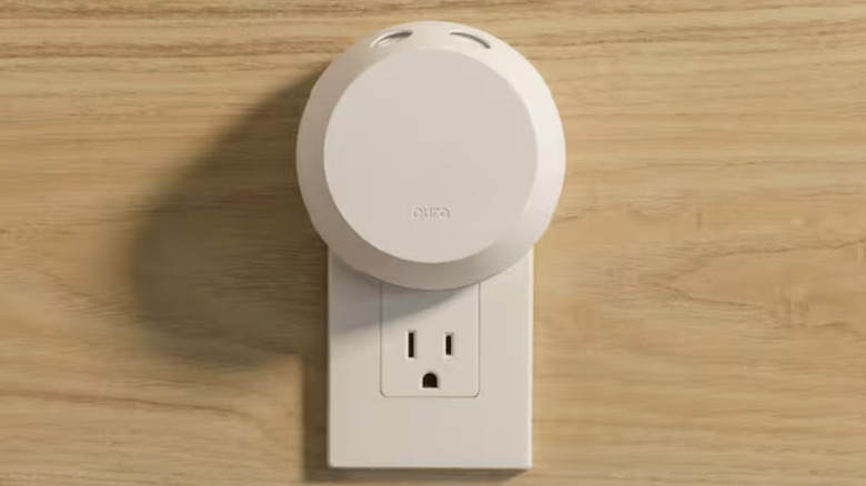 A Pura fragrance diffuser plugged into a wall socket