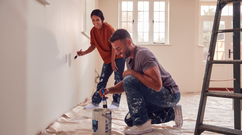 Young couple painting living room 