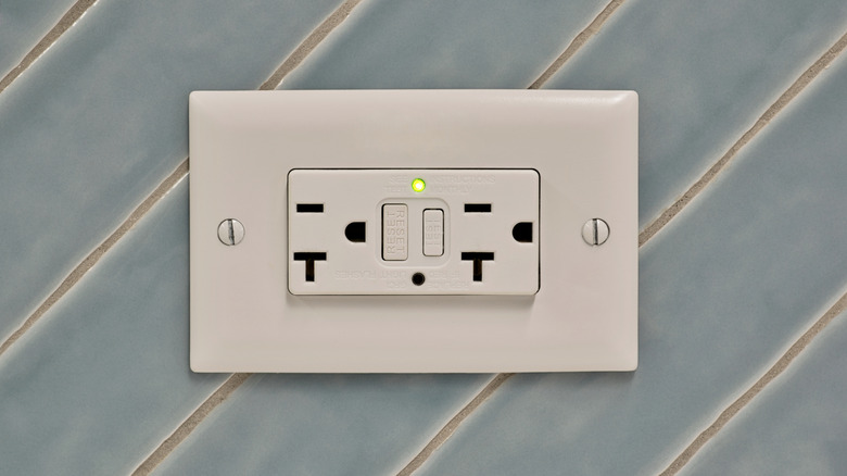 Closeup of an outlet on a tiled wall