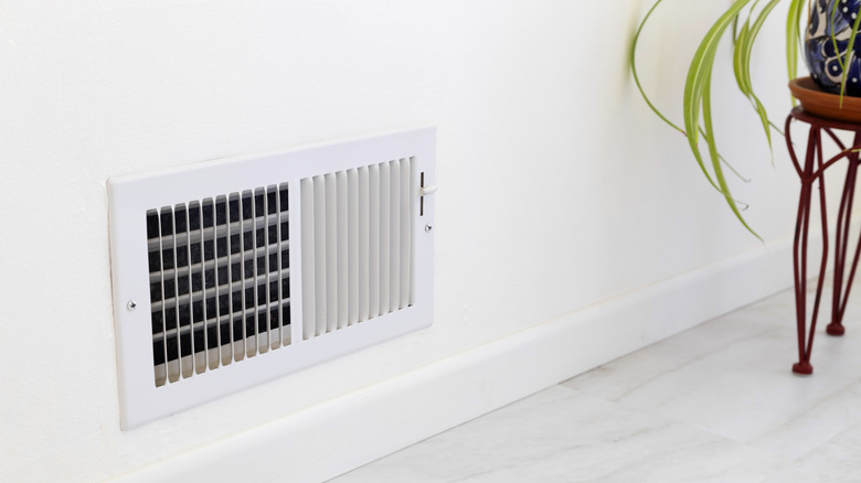 Closeup of an air vent in the wall near a plant